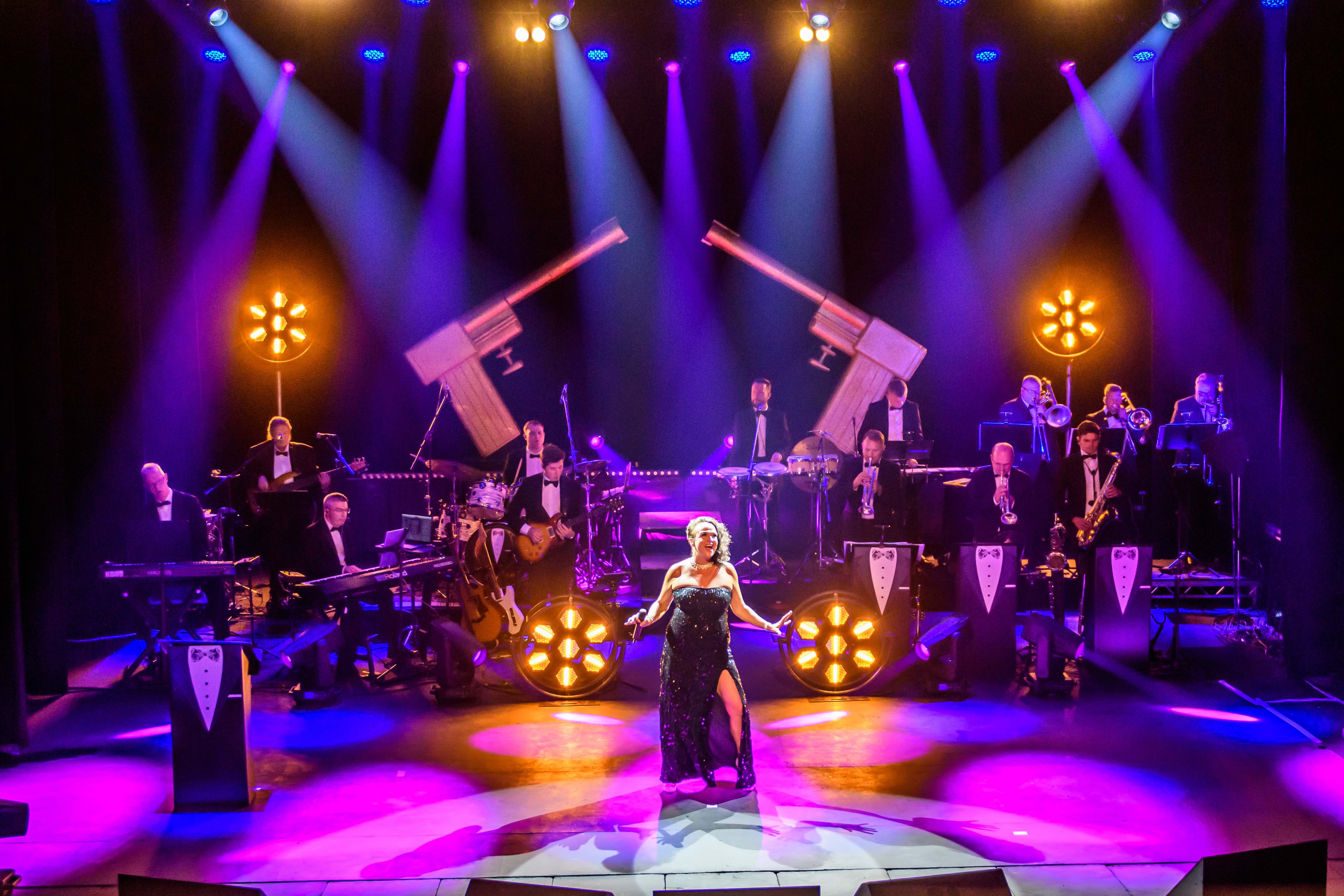 James Bond Themed Concert Spectacular featuring singers and a band on a theatre stage