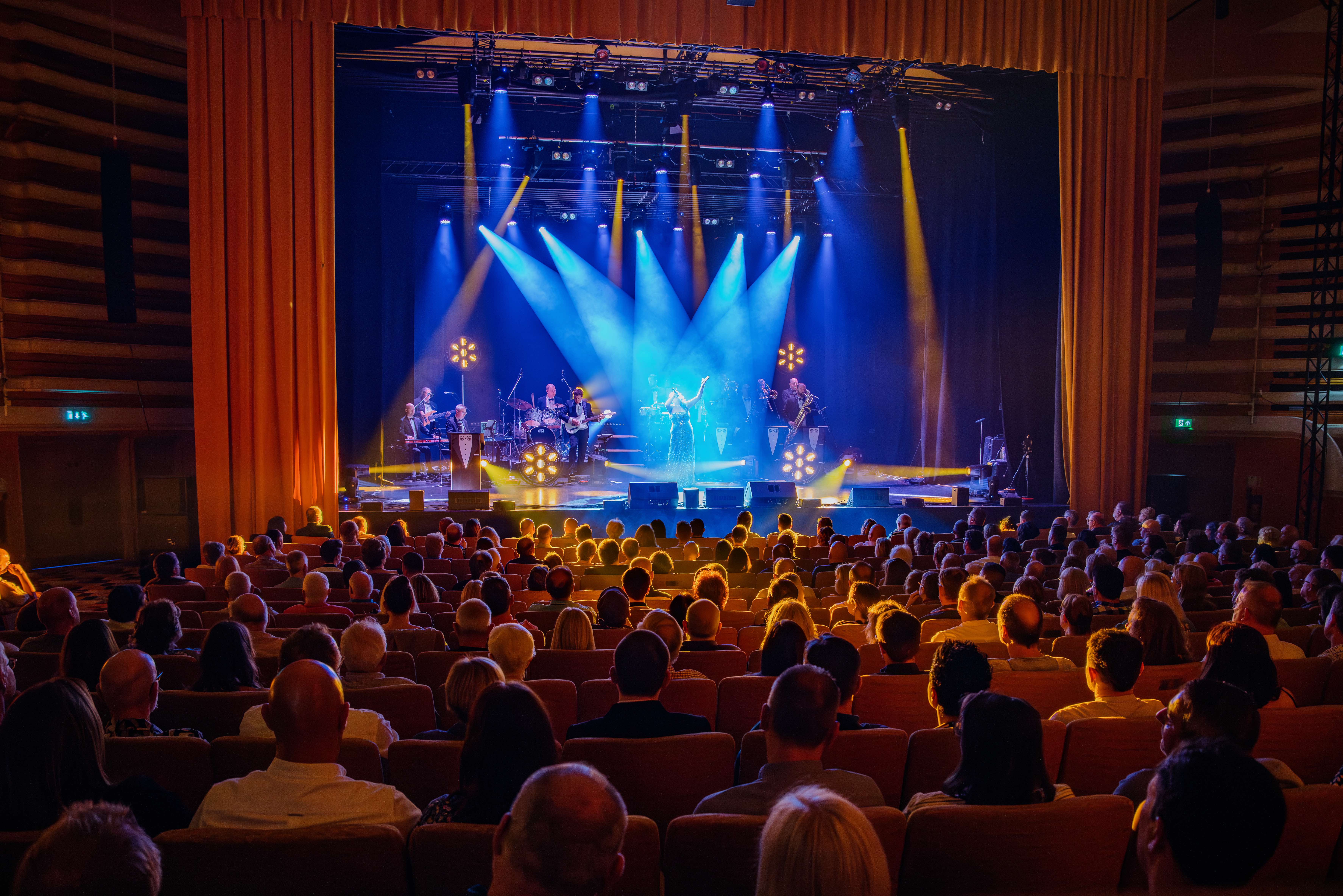 James Bond Themed Concert Spectacular featuring singers and a band on a theatre stage