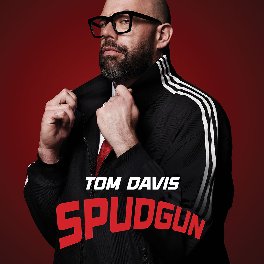 Comedian Tom Davis on a dark red background promoting his new tour Spudgun at the Victoria Theatre Halifax in 2027